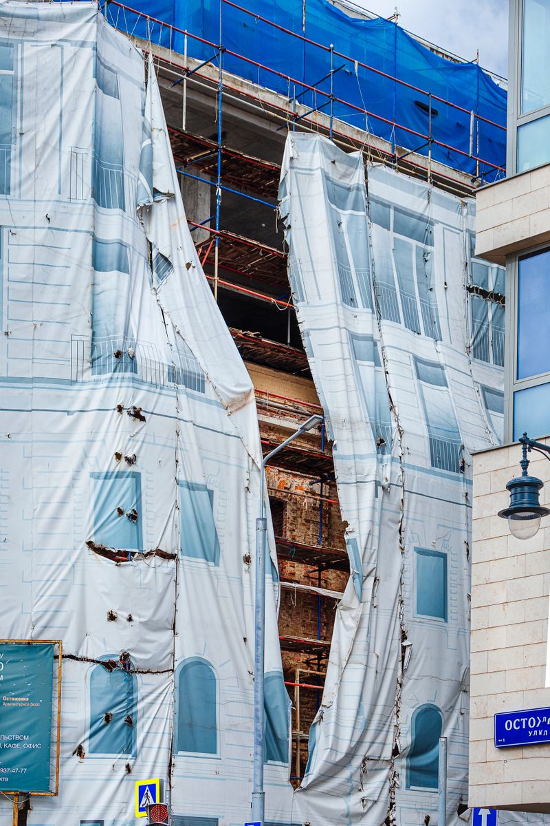 Building under renovation with scaffolding and protective sheets in an urban city environment.