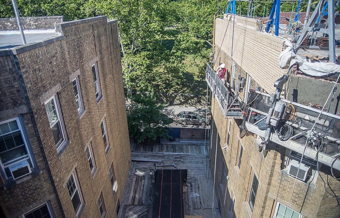 Facade restoration project involving parapet rebuilding, lintel replacement, and brick pointing using suspended scaffolding
